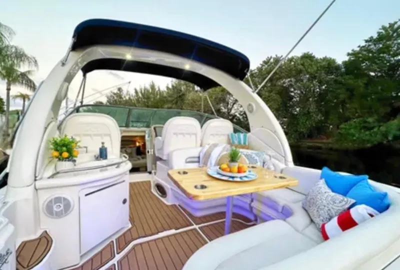 Slide: The Image of 2004 Sea Ray 340 Sundancer boat interior with seating and helm, docked near waterfront homes. - 3