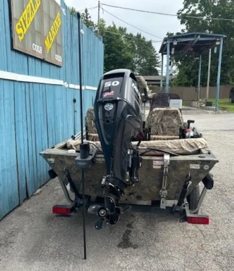 Slide: The Image of 2018 Tracker Grizzly 1648 SC boat with 50 HP motor, parked near blue building. - 5