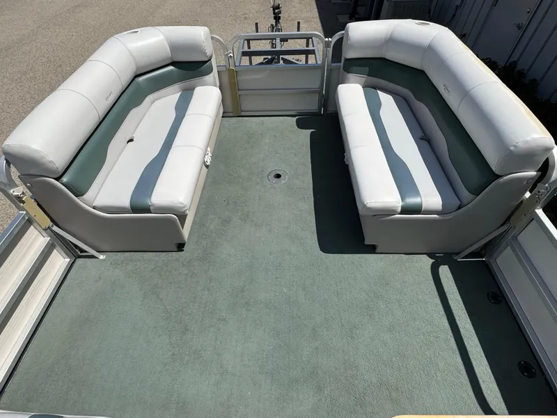 Slide: The Image of 2003 Sylvan 820 Mirage Cruise pontoon boat interior with cushioned seating and green carpet. - 9