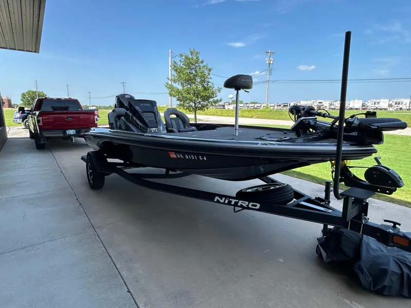 Slide: The Image of 2022 Nitro Z-18 boat on trailer, parked beside a red truck, under clear blue sky. - 3