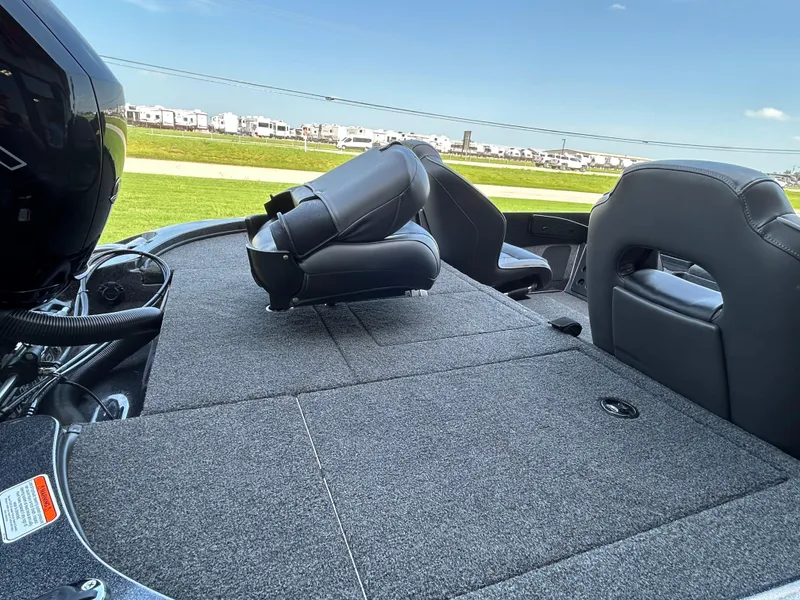 Slide: The Image of 2022 Nitro Z-18 boat interior with gray carpet and black seats, parked outdoors. - 7