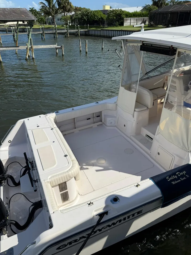 Slide: The Image of 2007 Grady-White Express 330 boat docked by waterfront, featuring spacious deck and seating area. - 11