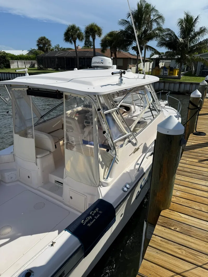 Slide: The Image of 2007 Grady-White Express 330 boat docked by a wooden pier, surrounded by palm trees. - 12