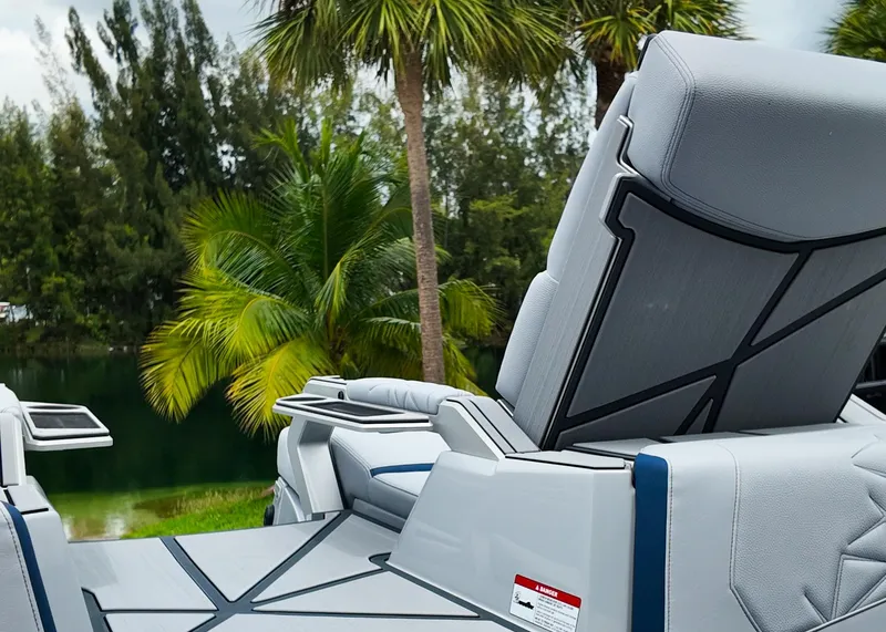 Slide: The Image of 2025 Nautique G23 Paragon boat interior with luxurious seating, set against a tropical backdrop. - 17