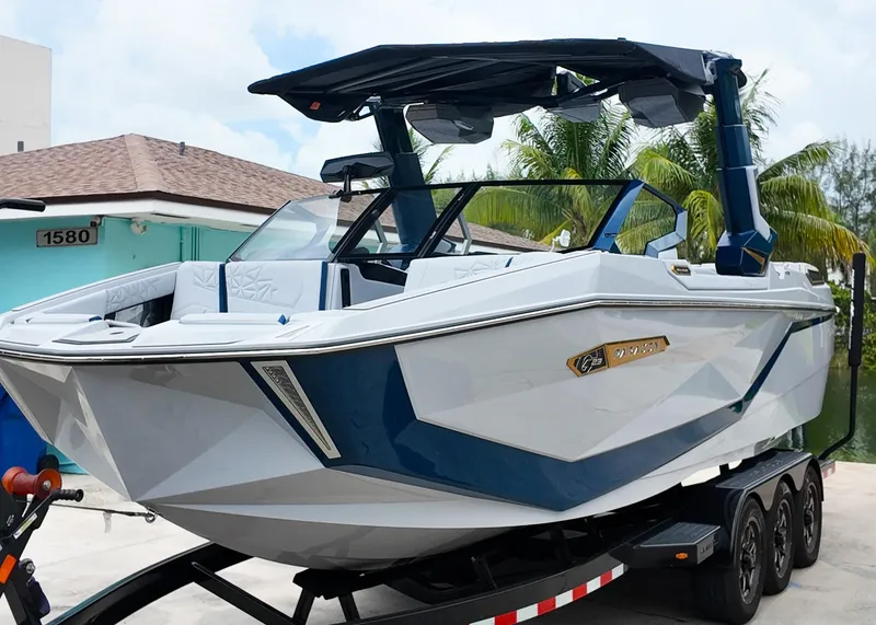 Slide: The Image of 2025 Nautique G23 Paragon boat on trailer, sleek design, blue and white color scheme. - 2