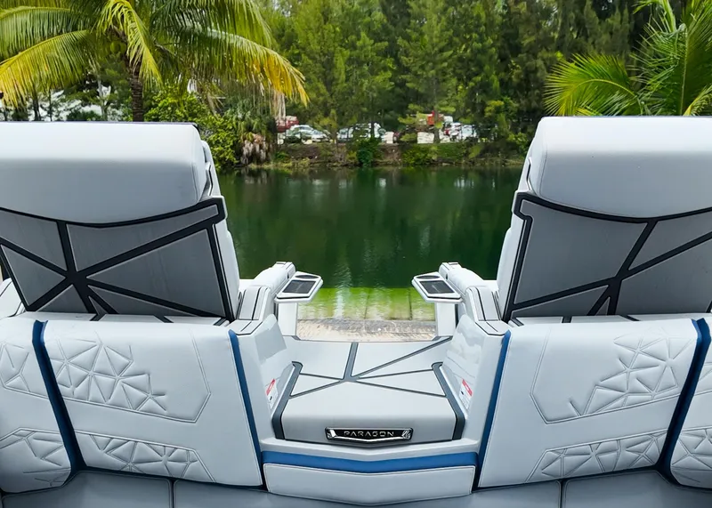 Slide: The Image of 2025 Nautique G23 Paragon boat seats overlooking a serene lake with lush greenery. - 24