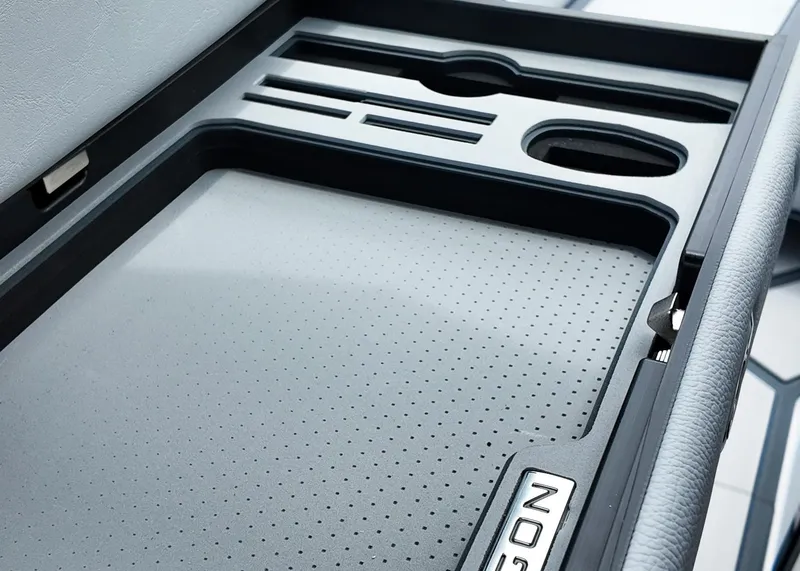 Slide: The Image of 2025 Nautique G23 Paragon interior storage compartment with sleek design and cup holders. - 6