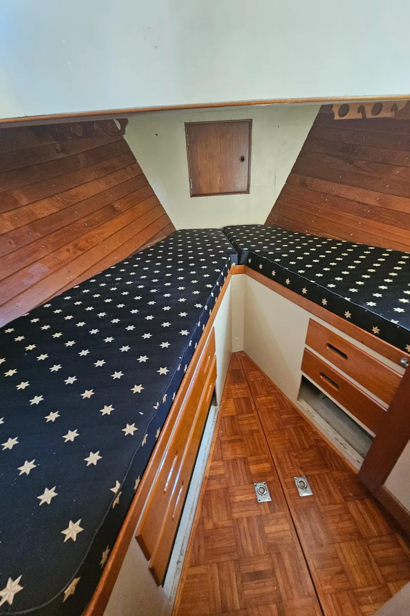 Slide: The Image of 1973 Grand Banks 36 Classic cabin interior with star-patterned bedding and wooden storage. - 12