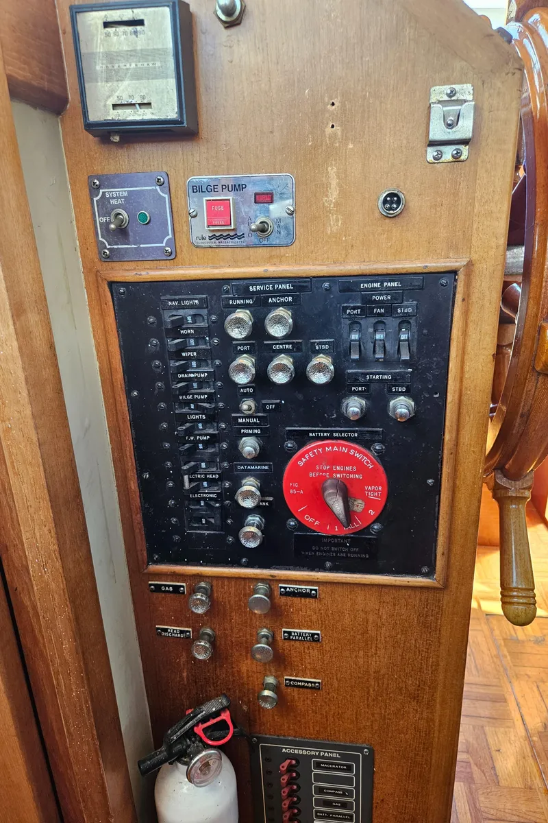 Slide: The Image of Control panel of a 1973 Grand Banks 36 Classic boat, featuring switches and a fire extinguisher. - 24