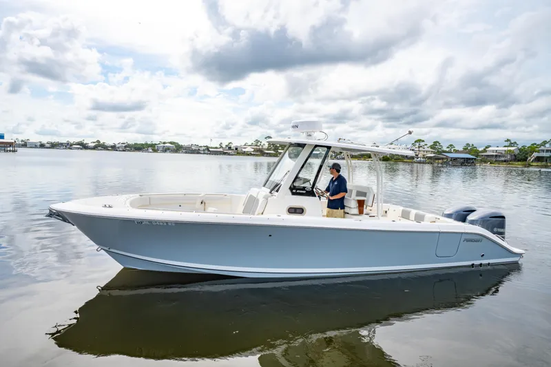 Slide: The Image of 2021 Pursuit S 288 Sport boat on calm water with a person at the helm. - 2