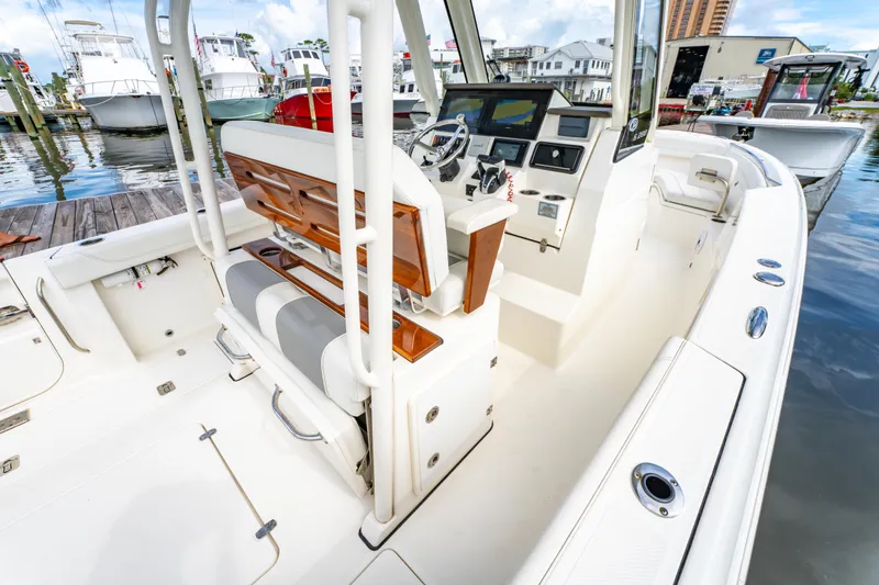Slide: The Image of 2021 Pursuit S 288 Sport boat interior with helm, seating, and docked boats in background. - 25