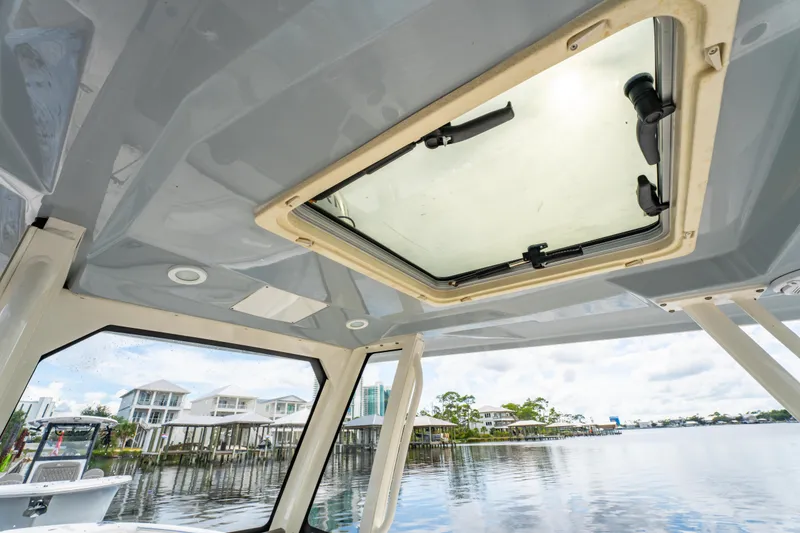 Slide: The Image of Interior view of 2021 Pursuit S 288 Sport boat with sunroof and waterfront houses. - 37
