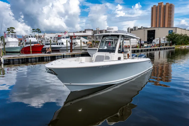 Slide: The Image of 2021 Pursuit S 288 Sport boat docked in a marina with cityscape background. - 5