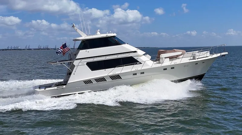 The Image of 1988 Hatteras Enclosed Bridge Sportfish yacht cruising on open water under blue skies. - 0