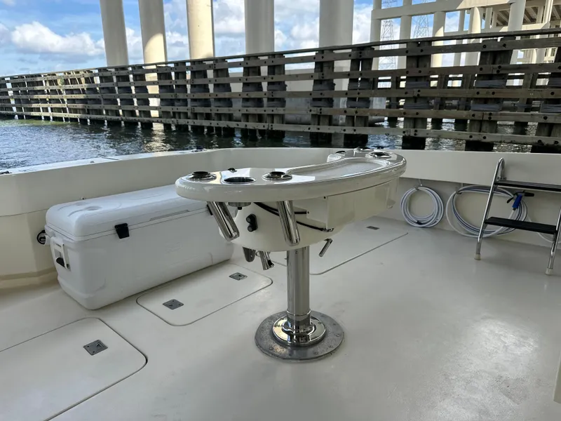 Slide: The Image of 1988 Hatteras Enclosed Bridge Sportfish deck with fishing station and cooler under a bridge. - 23