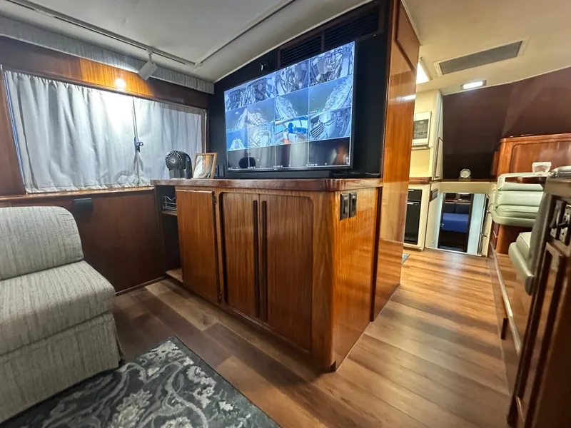 Slide: The Image of 1988 Hatteras Enclosed Bridge Sportfish interior with wood paneling and surveillance screens. - 46