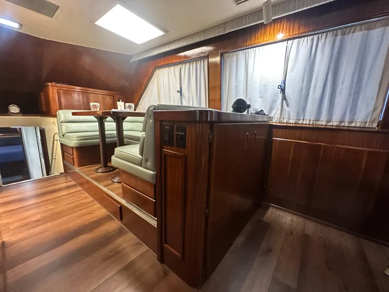 Slide: The Image of 1988 Hatteras Enclosed Bridge Sportfish interior with wood paneling and green seating. - 48