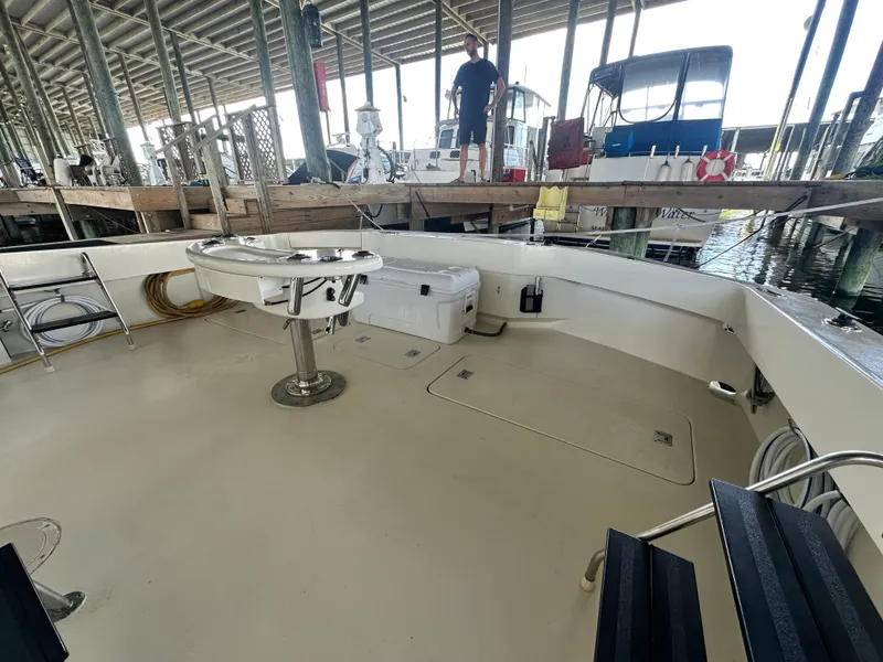 Slide: The Image of 1988 Hatteras Enclosed Bridge Sportfish boat deck in marina, featuring fishing chair and equipment. - 26