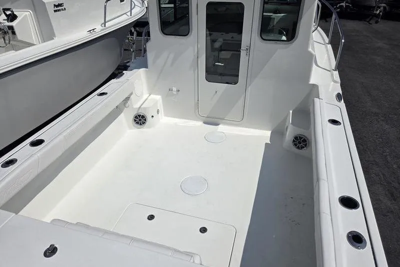 Slide: The Image of 2026 Parker 2220 SPORT CABIN boat deck, spacious and clean with rod holders and speakers. - 6