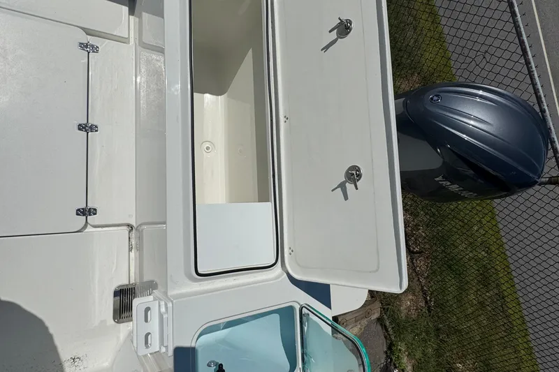 Slide: The Image of 2025 Parker 2220 SC boat deck with open storage compartments and outboard motor. - 14