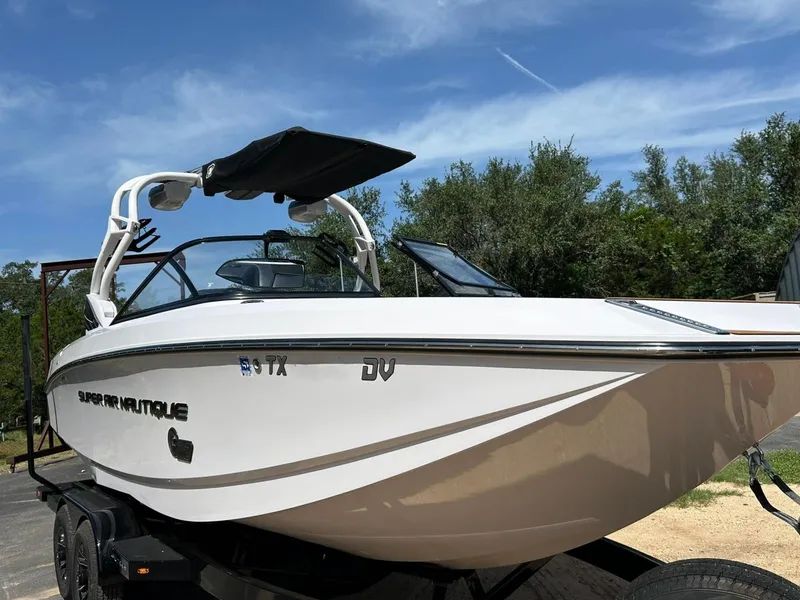 Slide: The Image of 2014 Nautique Super Air Nautique G23 boat on trailer, under clear blue sky. - 11