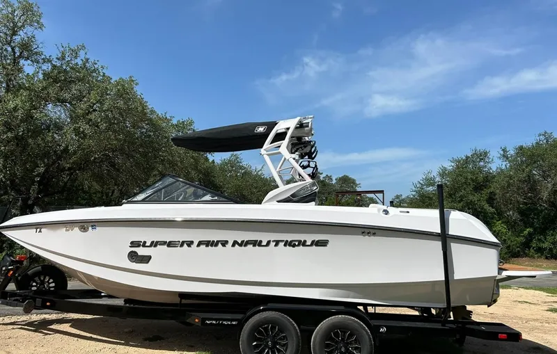 Slide: The Image of 2014 Nautique Super Air Nautique G23 boat on trailer, parked outdoors under blue sky. - 13