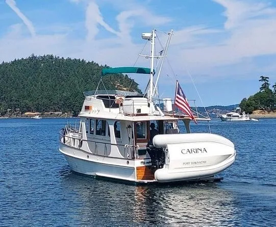 Slide: The Image of 1990 Grand Banks 36 Europa yacht on serene water with lush green island backdrop. - 1
