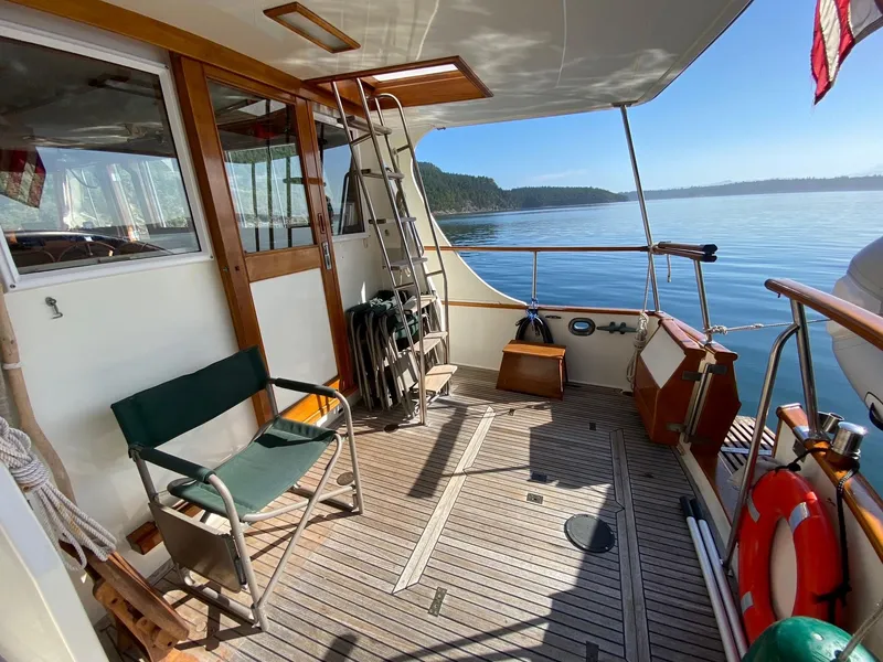 Slide: The Image of 1990 Grand Banks 36 Europa yacht deck with seating, ladder, and scenic water view. - 17