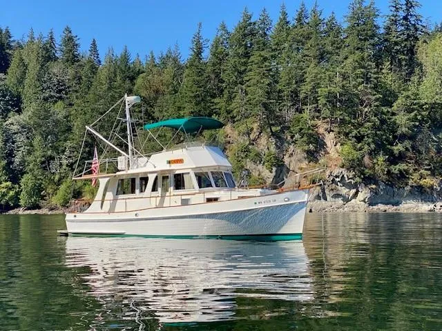 Slide: The Image of 1990 Grand Banks 36 Europa yacht on calm water, surrounded by lush forest. - 2