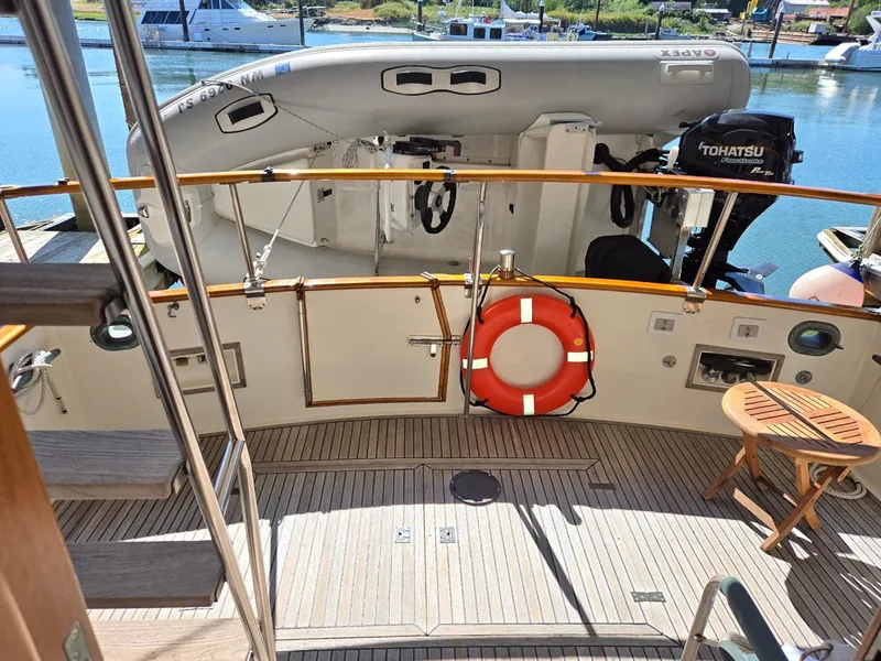 Slide: The Image of Grand Banks 36 Europa yacht deck with lifebuoy, outboard motor, and wooden seating, 1990 model. - 20