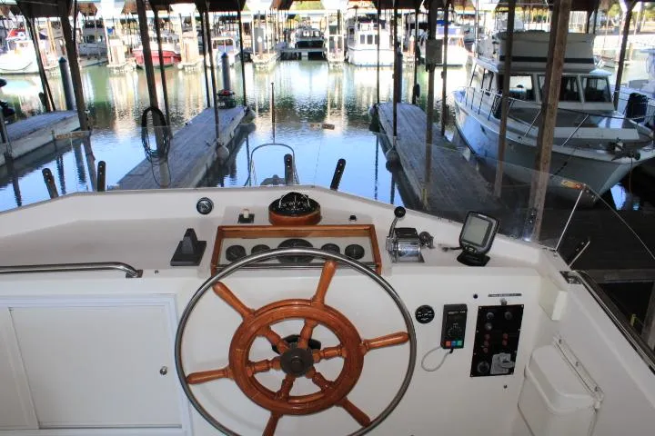 Slide: The Image of Helm of 1990 Grand Banks 36 Europa yacht in marina, featuring classic wooden steering wheel. - 27