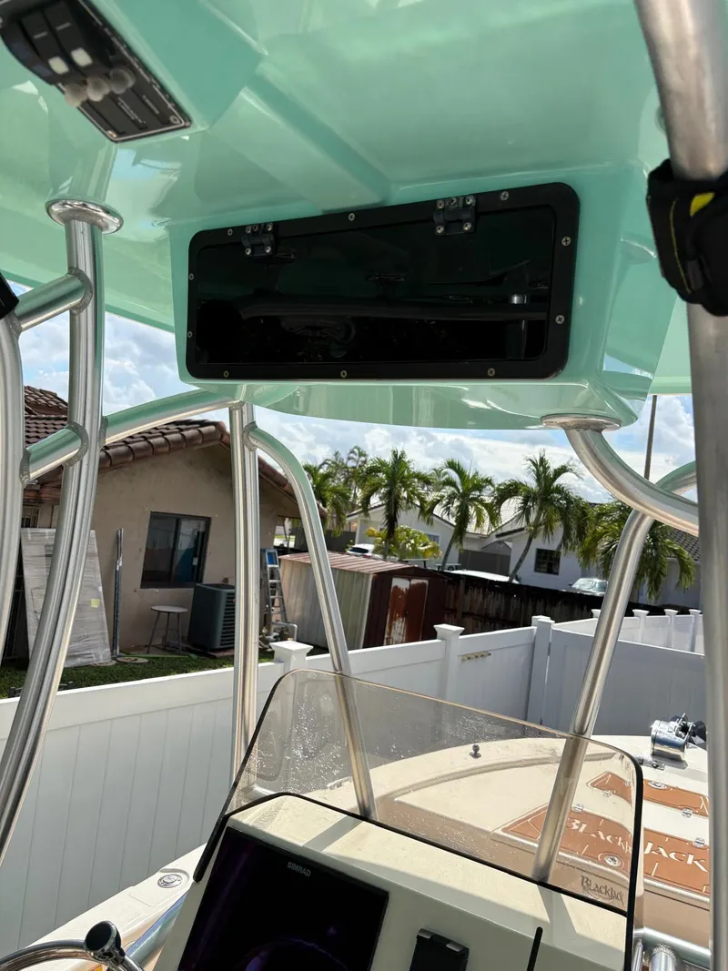 Slide: The Image of 2019 BlackJack 224 boat interior with T-top and console, outdoor setting. - 18
