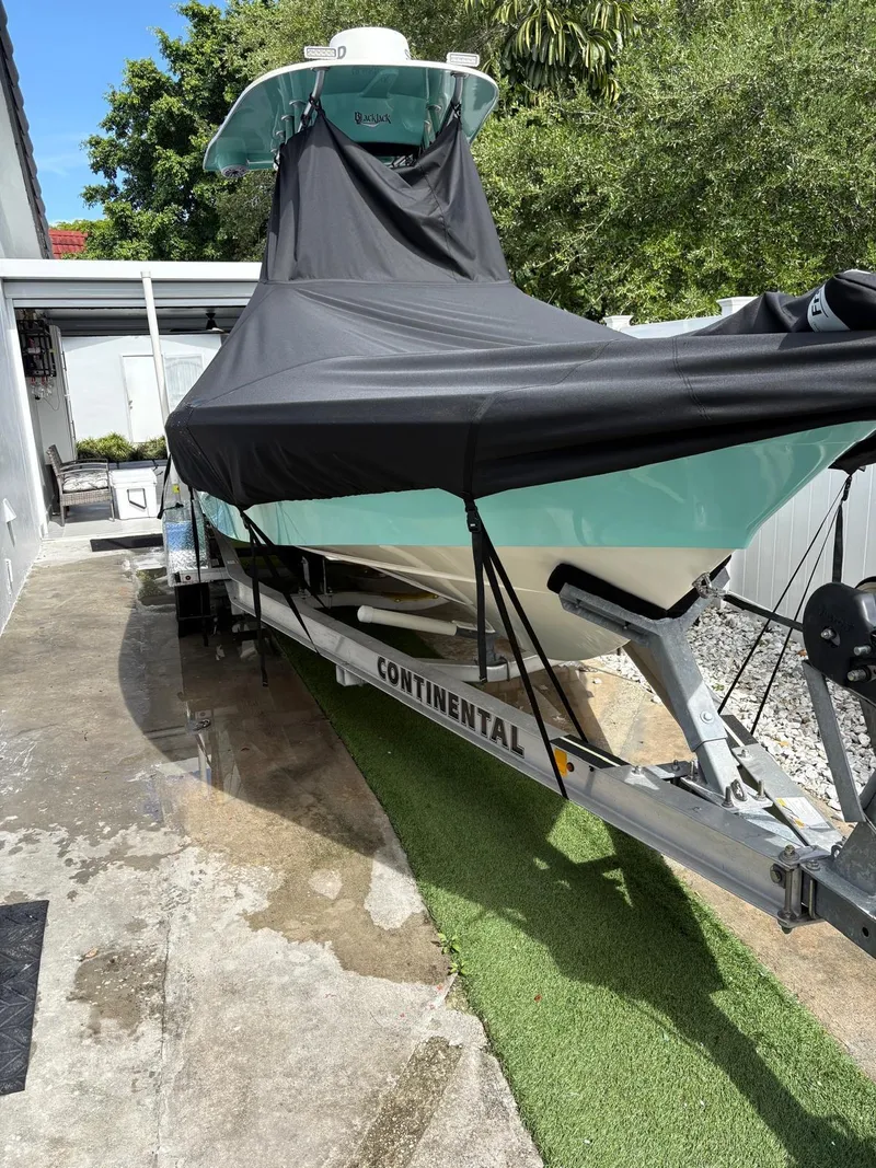 Slide: The Image of 2019 BlackJack 224 boat on Continental trailer, covered, parked on driveway. - 34