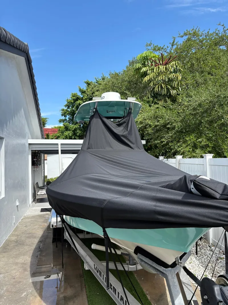 Slide: The Image of Covered BlackJack 224 boat on trailer, parked beside a house, under clear blue sky. - 35