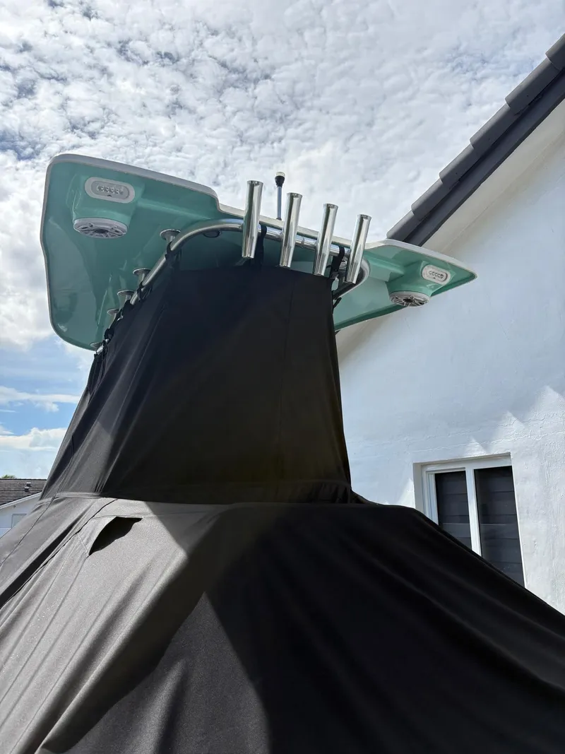 Slide: The Image of Covered BlackJack 224 boat with T-top, 2019 model, against a cloudy sky backdrop. - 45