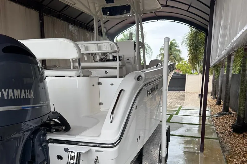 Slide: The Image of 2017 Century 2600 Center Console boat under canopy, parked beside a car. - 2