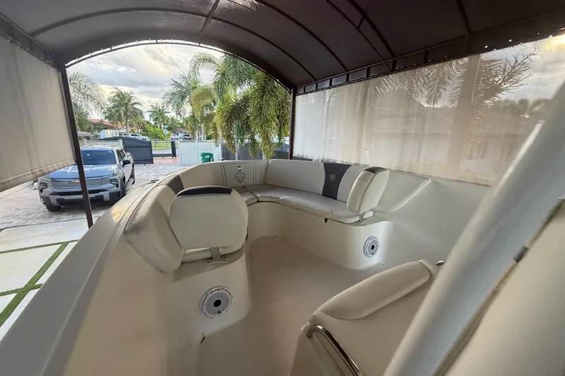 Slide: The Image of 2017 Century 2600 Center Console boat interior with cushioned seating, parked near palm trees. - 20
