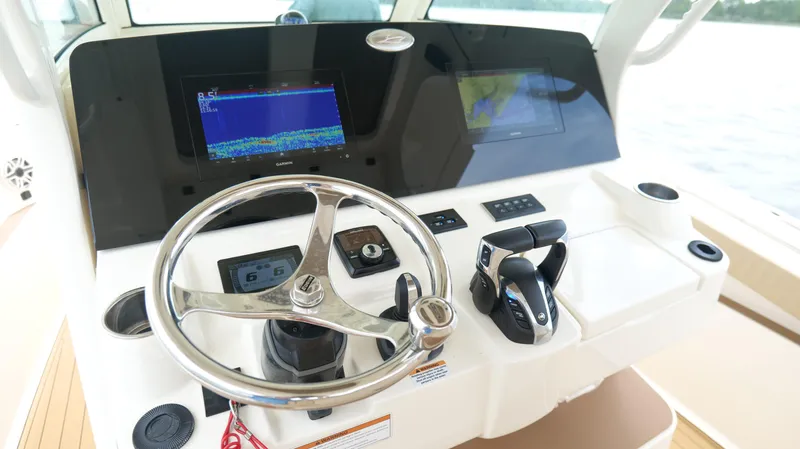 Slide: The Image of 2022 Scout 330 LXF boat dashboard with steering wheel and navigation screens. - 12
