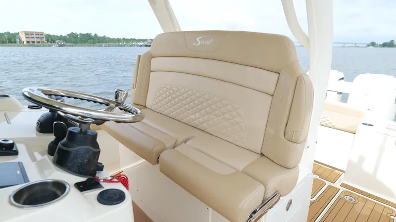 Slide: The Image of 2022 Scout 330 LXF boat interior with beige seating and steering wheel. - 22