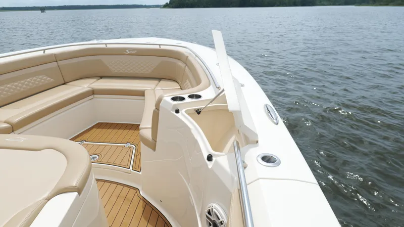 Slide: The Image of 2022 Scout 330 LXF boat interior with tan seating and open storage on a calm lake. - 39