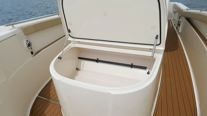 Slide: The Image of Open storage compartment on 2022 Scout 330 LXF boat with teak flooring. - 48