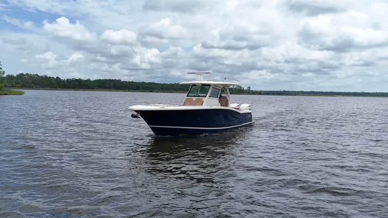 Slide: The Image of 2022 Scout 330 LXF boat on a calm lake under cloudy skies. - 5