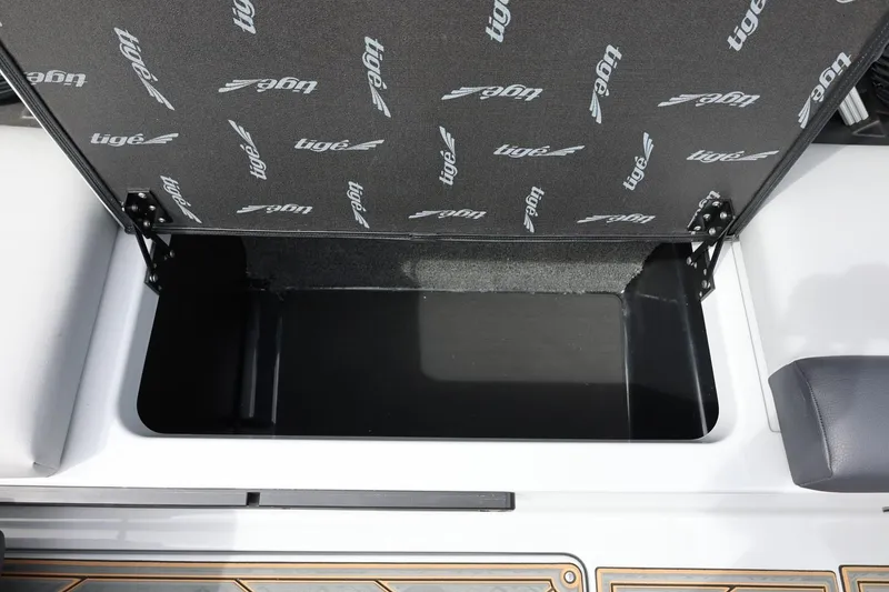 Slide: The Image of Open storage compartment in 2025 Tigé Z3 boat, featuring branded interior lid. - 27