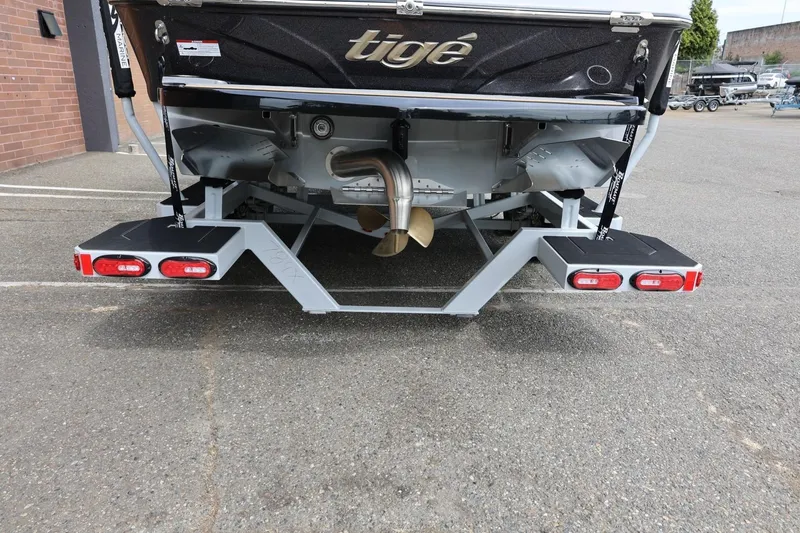 Slide: The Image of 2025 Tigé Z3 boat rear view with propeller and platform, parked on pavement. - 8