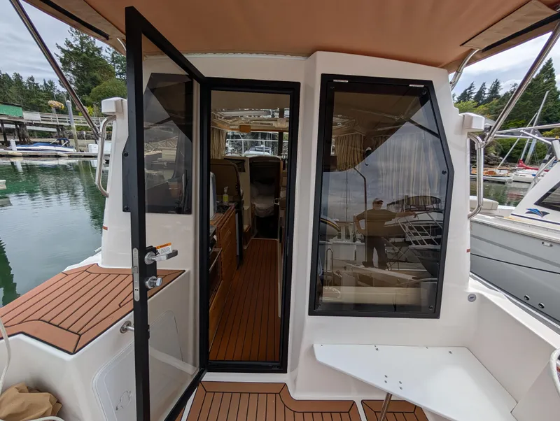 Slide: The Image of 2024 Ranger Tugs R27-OB boat interior with open door, docked at marina. - 10