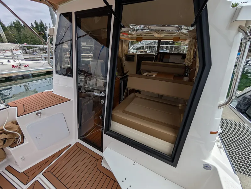 Slide: The Image of 2024 Ranger Tugs R27-OB boat interior view with open door and seating area. - 11