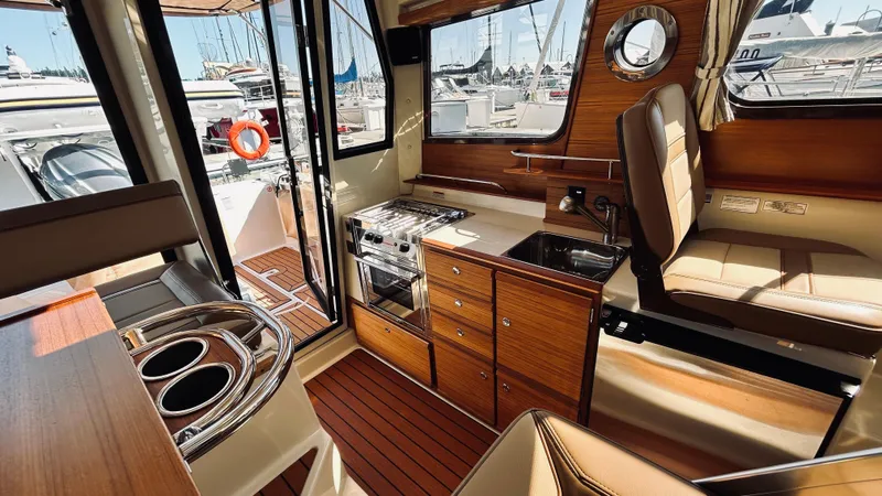 Slide: The Image of 2024 Ranger Tugs R27-OB interior with wood finish, kitchenette, and seating area. - 12