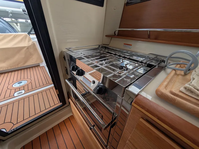 Slide: The Image of 2024 Ranger Tugs R27-OB interior kitchen with stove and wooden flooring. - 13