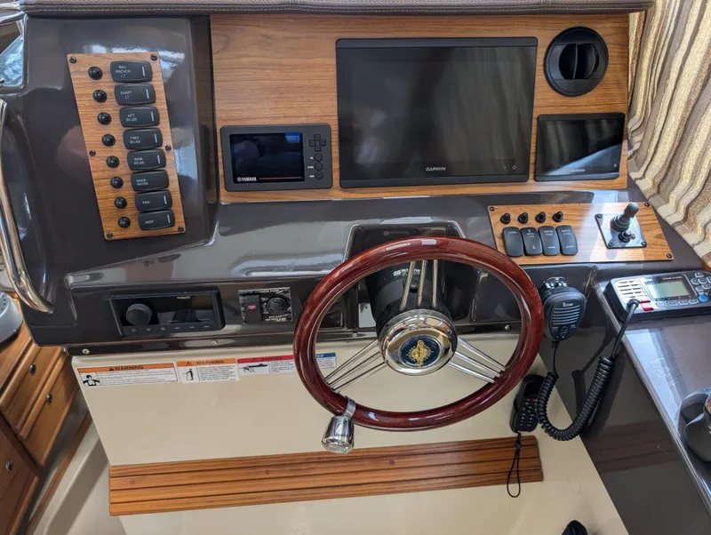 Slide: The Image of 2024 Ranger Tugs R27-OB helm with steering wheel, navigation controls, and electronic displays. - 16