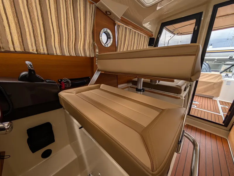 Slide: The Image of 2024 Ranger Tugs R27-OB interior with tan seating and wood accents. - 17